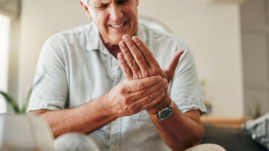 Older man squeezing left hand in pain