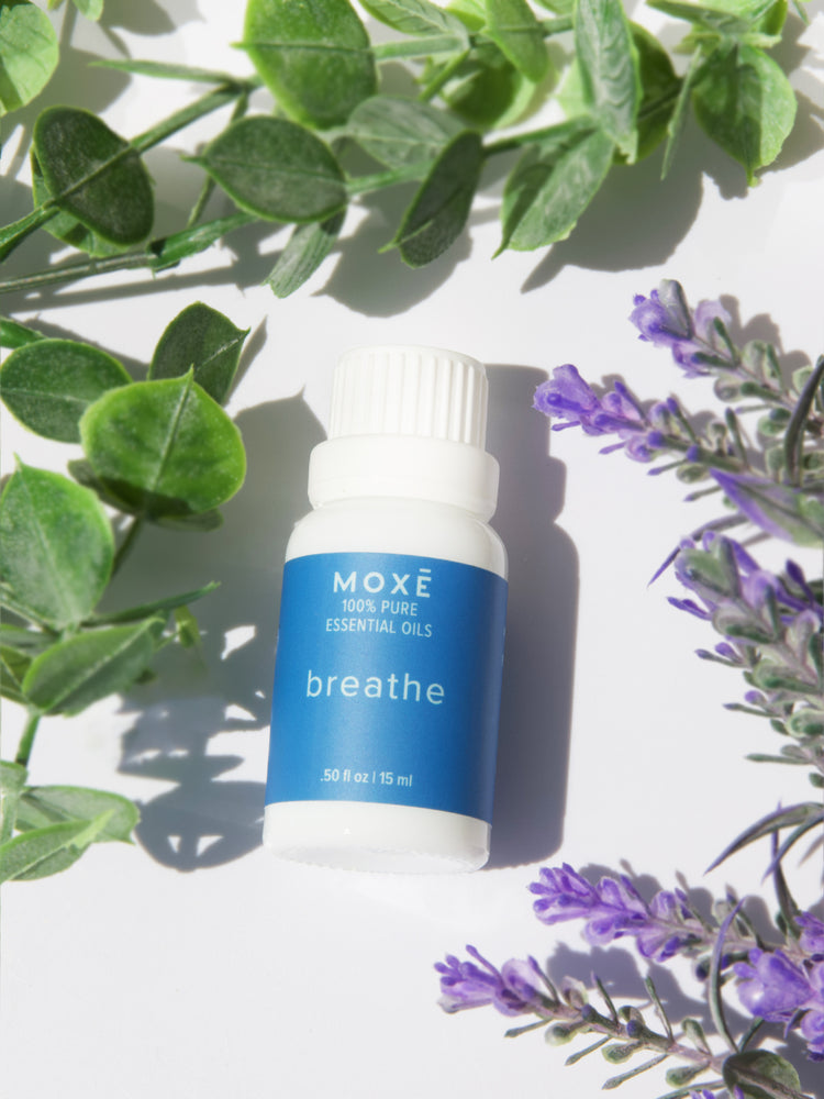 MOXĒ Breathe Essential Oil on a table with plants
