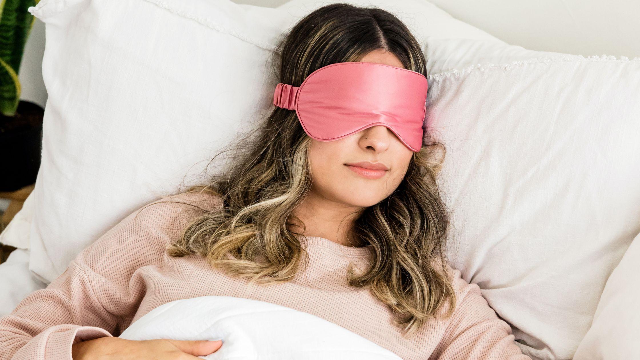 Woman sleeping in bed with pink eye mask on