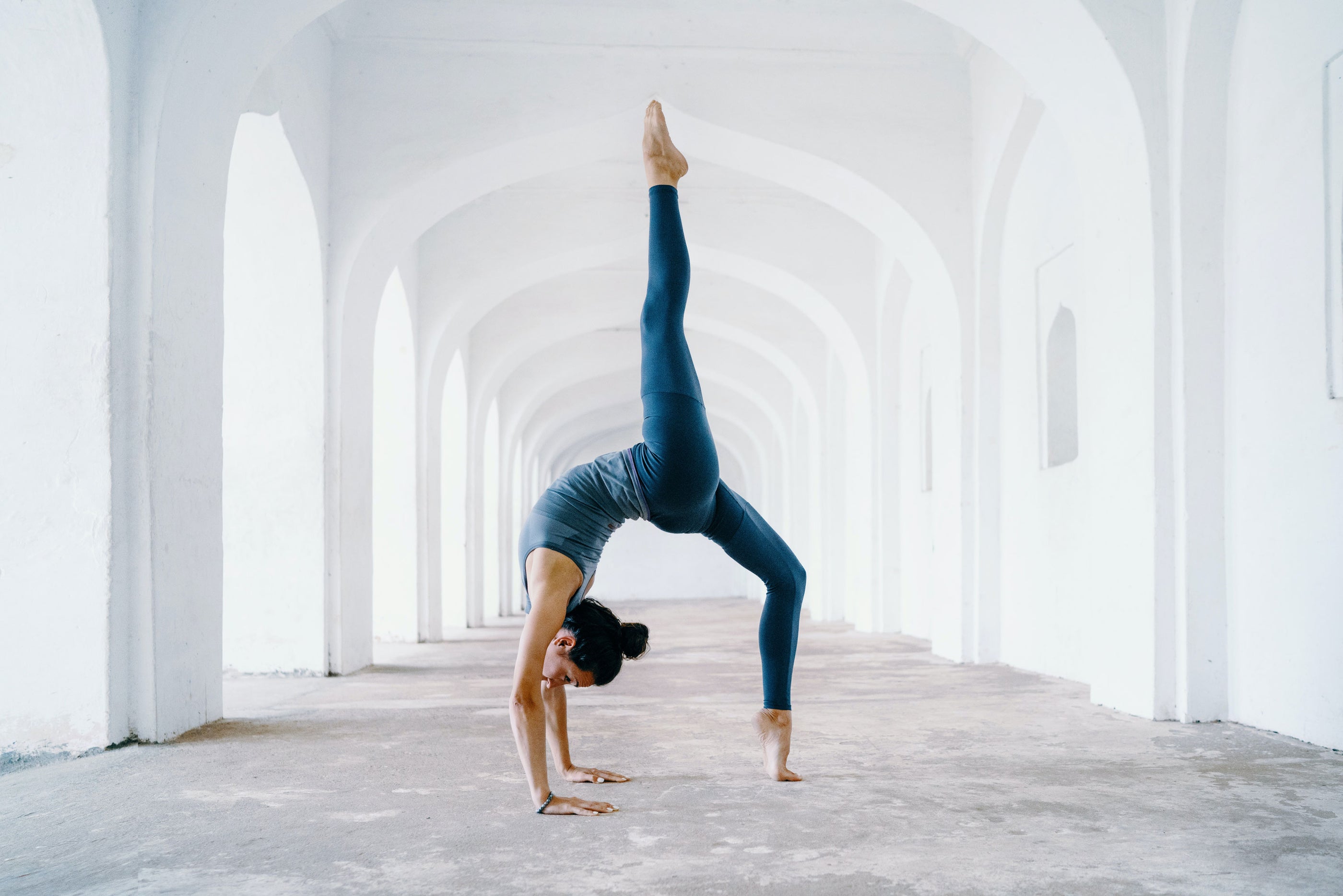 Women doing yoga pose in a long tunnel of white archways