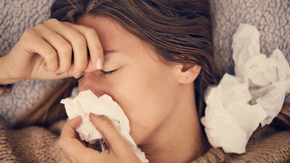 Woman laying down sick blowing her nose 