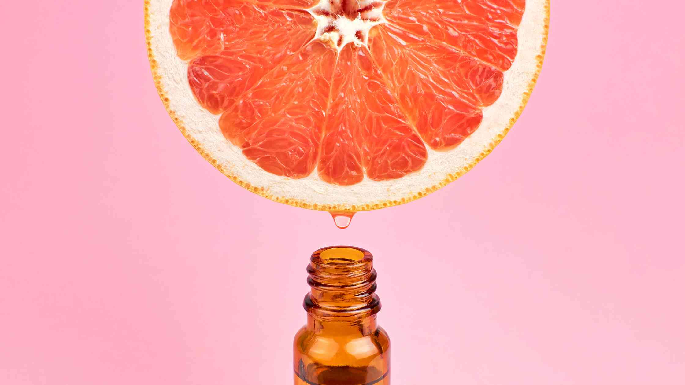 Fresh grapefruit juice being poured from above into an essential oil bottle