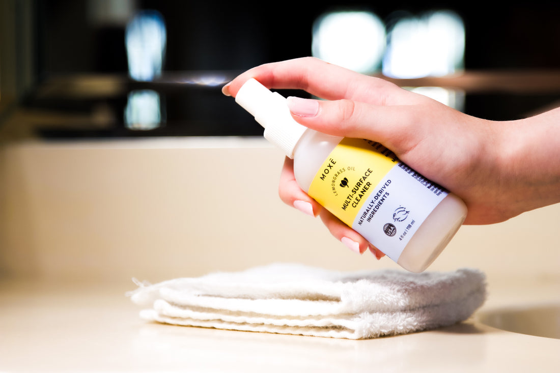 Hand spraying countertop with moxe multi-surface plant based cleaner spray