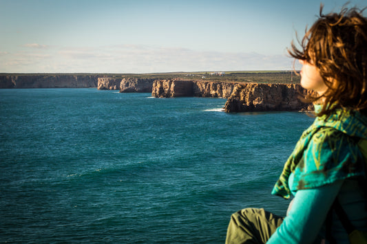 Girl with long hair blowing in the wind looking out across the ocean