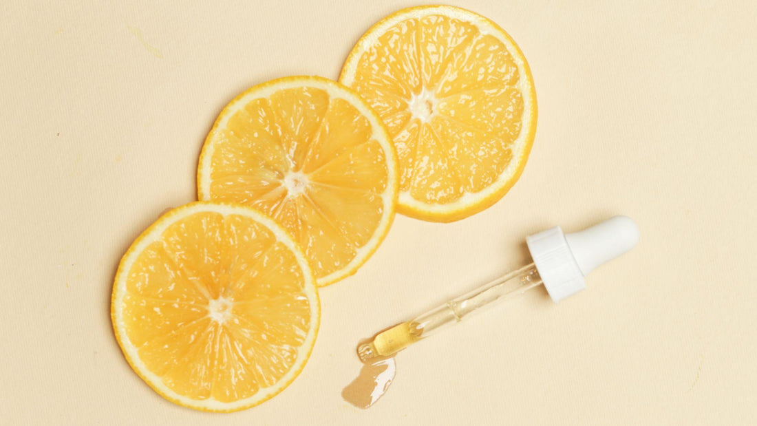 Three lemon slices sitting next to a dropper full of lemon essential oil
