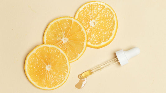 Three lemon slices sitting next to a dropper full of lemon essential oil