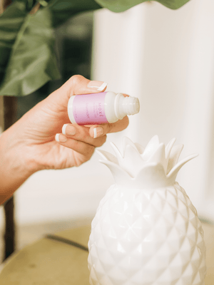 Hand pouring MOXĒ Lavender Essential Oil into pineapple-shaped diffuser