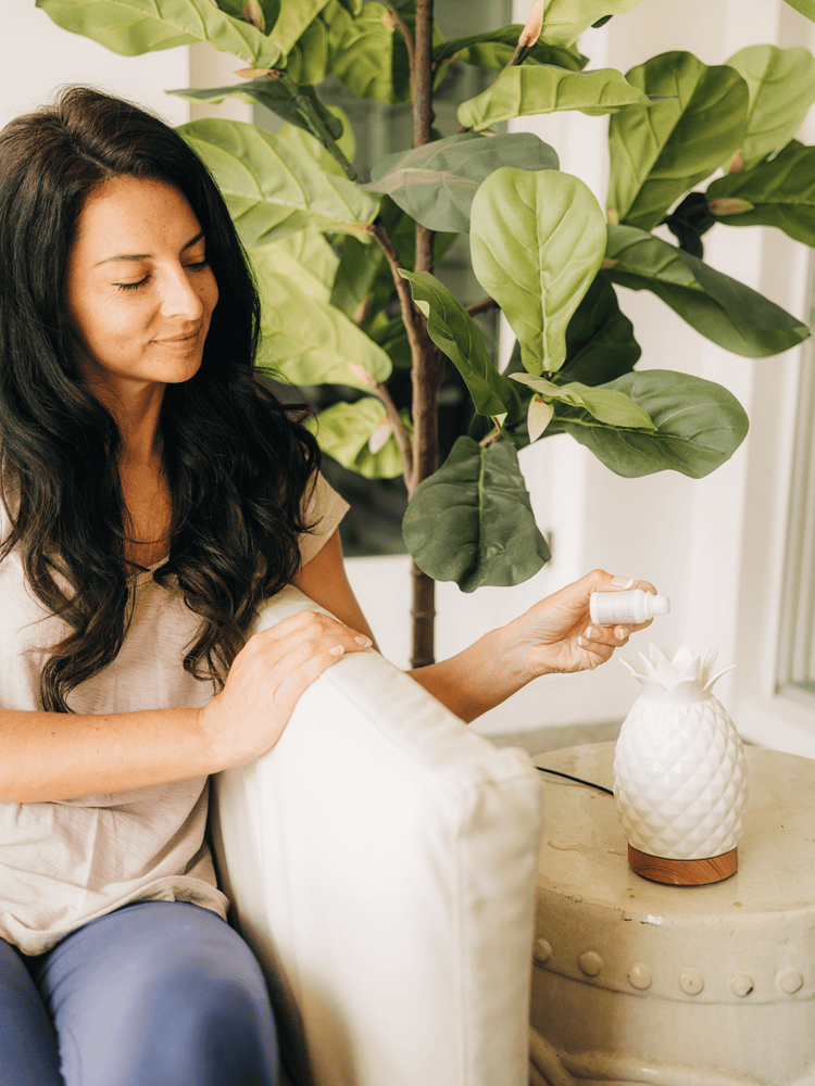 Woman pouring MOXĒ Lavender Essential Oil into pineapple-shaped diffuser