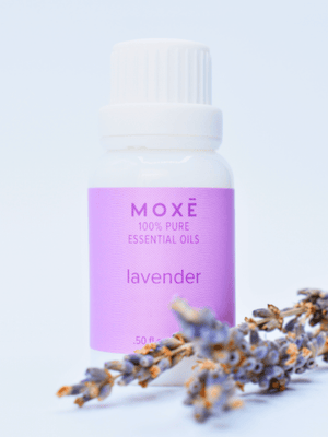 MOXĒ Lavender Essential Oil sitting behind fresh lavender
