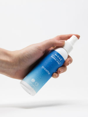 Bottle of MOXĒ Breathe Shower Spray with a hand holding it