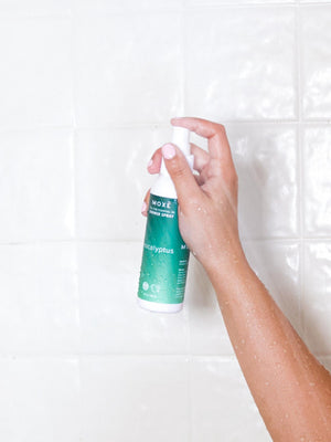 MOXĒ Eucalyptus Shower Spray with a hand holding it in the shower