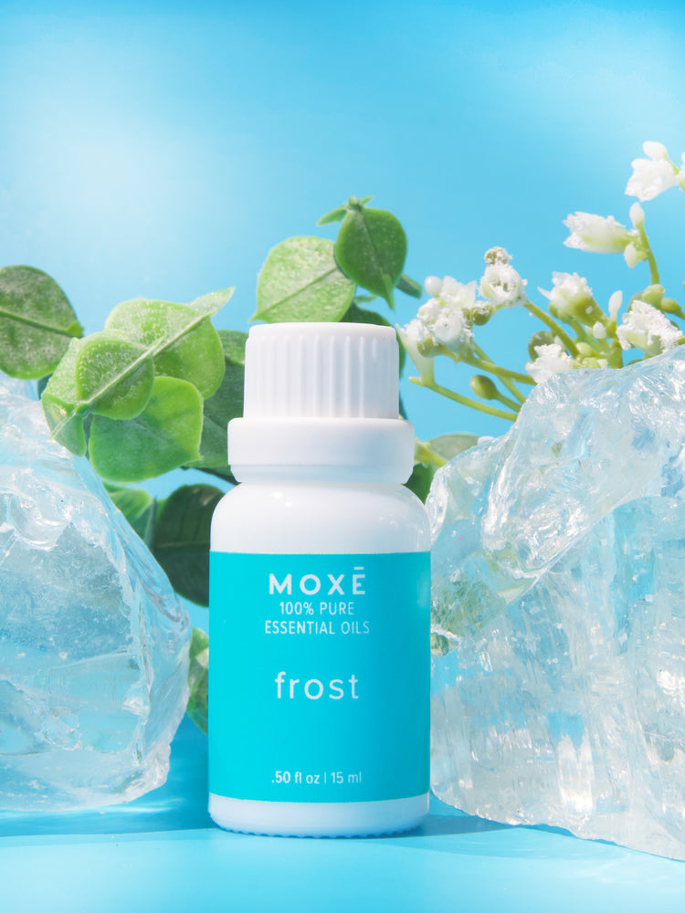 MOXĒ Frost Essential Oil on a table with plants