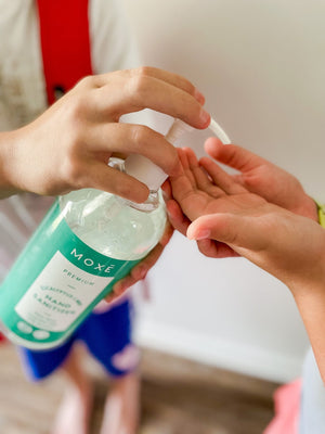 Kid using MOXE Eucalyptus Mint Hand Sanitizer in other kid's hand