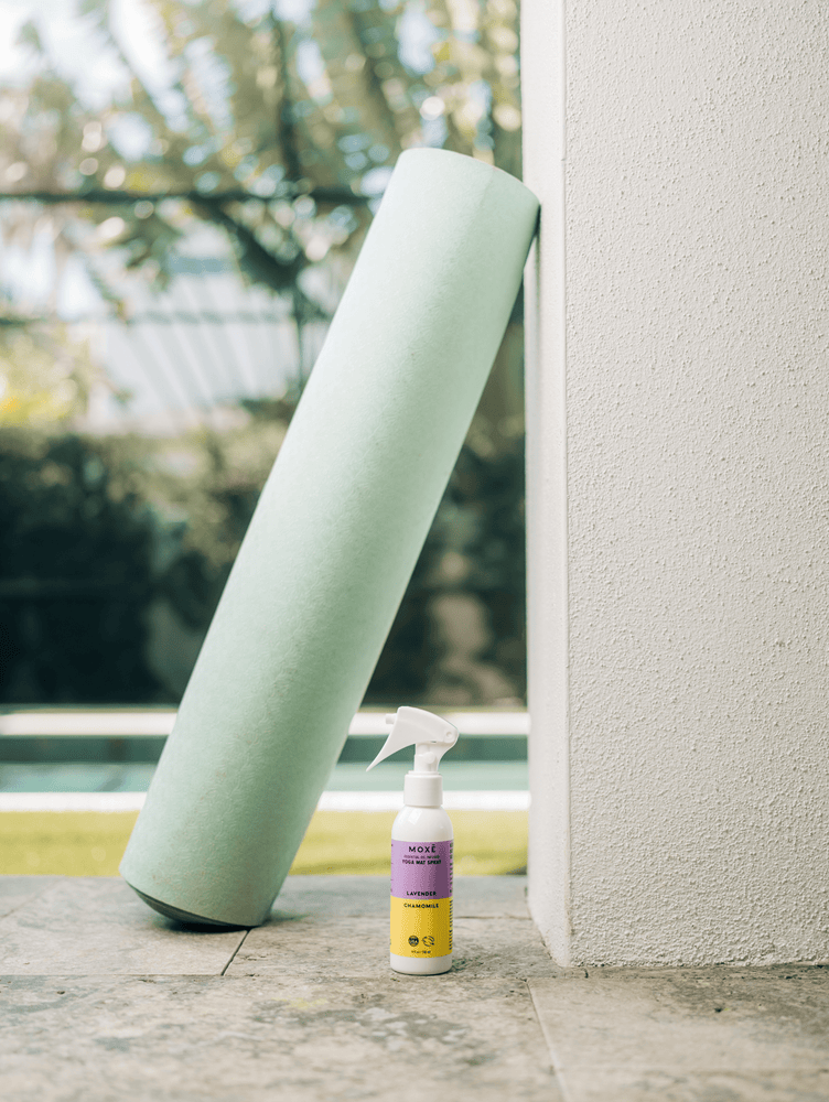 MOXĒ Lavender Chamomile Yoga Mat Spray sitting below rolled yoga mat