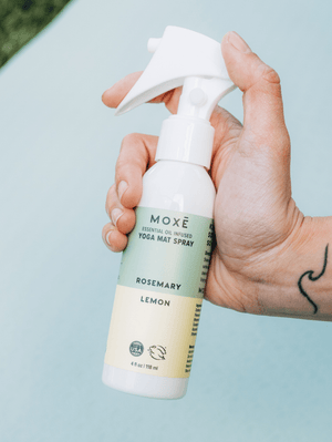 
                
                    Load image into Gallery viewer, Hand holding the MOXĒ Rosemary Lemon Yoga Mat Spray 
                
            