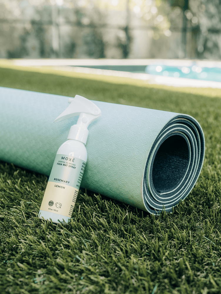 
                
                    Load image into Gallery viewer, MOXĒ Rosemary Lemon Yoga Mat Spray leaning against green yoga mat
                
            